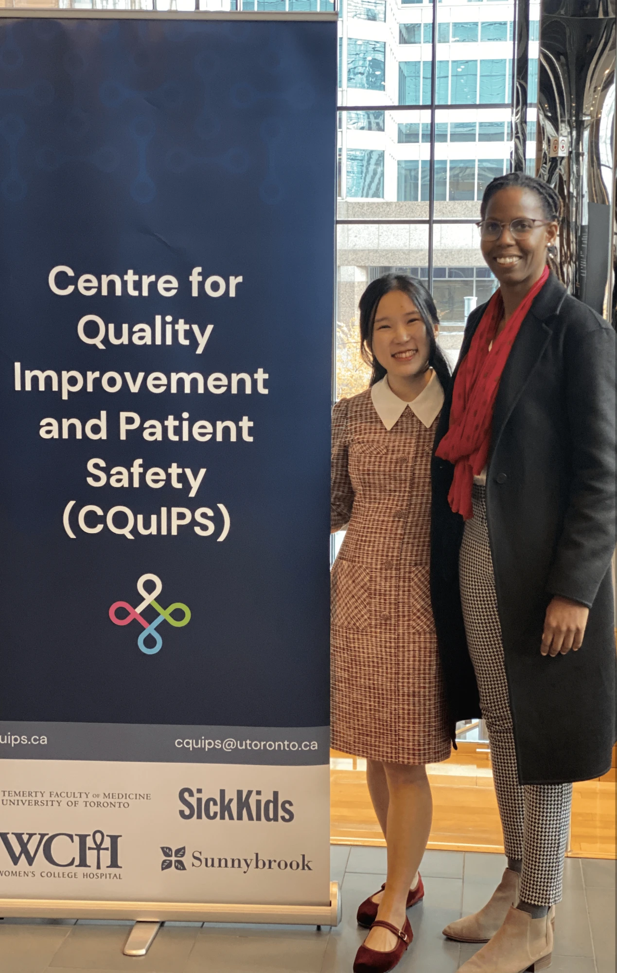 Two people smiling next to a Centre for Quality Improvement and Patient Safety banner